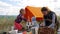 Parents and kids having a picnic and they are going to stay overnight in a tent. Traveler woman and children relaxing