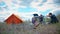 Parents and kids having a picnic and they are going to stay overnight in a tent. Traveler woman and children relaxing