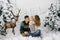 Parents kiss their son and sit on artificial snow in the photo zone for Christmas and new Year in the winter