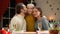 Parents kissing happy child, looking at camera, Christmas tree twinkling behind