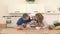 Parents are kissing their son. A child prepares a fruit salad in the kitchen for mom and dad.