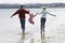 Parents Lifting Daughter While Walking Along Beach