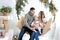 Parents with little girl are swinging on a swing, decorated with Christmas decorations