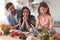 Parents looking daughter stirring salad on the kitchen