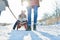 Parents pull child with sled in the snow