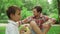 Parents relaxing on blanket in park with kids. Children blowing soap bubbles