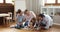 Parents and siblings play game seated on floor at home