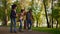 Parents teaching girl riding longboard in park. Supportive family encourage kid.