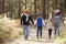 Parents and three children walking in a forest, front view