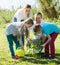 Parents with two kids planting a bush