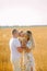Parents walk with their baby and kiss his among wheat field