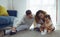 Parents warmth by embracing and teasing little daughter while spend time together on floor in living room at home. Mom and Dad