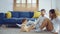 Parents warmth by embracing and teasing little daughter while spend time together on floor in living room at home. Mom and Dad