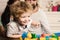 Parents watch their son play with colorful blocks.