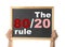 Pareto principle concept. Woman holding blackboard with 80/20 rule representation on background, closeup