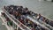 Paris, France - 3 May 2023. Top view from bridge to excursion double-deck boat with crowd tourists on board floating on