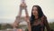 Paris woman smiling eating the french pastry macaron in Paris against Eiffel tower.