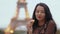 Paris woman smiling eating the french pastry macaron in Paris against Eiffel tower.