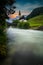 The parish church of St. Sebastian in Ramsau near Berchtesgaden as a long exposure with the river and a bridge at sunset