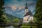 The parish church of St. Sebastian in Ramsau near Berchtesgaden as a long exposure with the river and a bridge at sunset