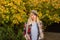 Parisian fashion style. Stylish blonde girl wearing plaid scarf and cap at fall autumnal yellow leaves background