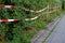 Park area surrounded with red and white barrier tape around a hedge.