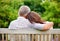 Park, back view or mature couple on bench for support, trust or hope in commitment together in nature. Hug, garden or