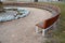 Park bench in the shape of a circle or crescent. on the square with an ornamental flowerbed around the monument. perennial flowerb