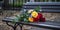 A park bench with a small bouquet of rainbow-colored flowers left behind, symbolizing an lgbt couple recent visit