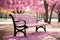 a park bench is surrounded by pink blossoms