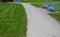 Park benches in light blue made of metal strips similar to a lattice. trash can and beautiful lawn with park paths of gravel thres