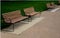 Park benches lined with wood along the entire wide threshing gravel beige path, lawns, flower lush, perennial flower beds blooming