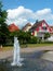 Park with fountain and red houses with blue sky