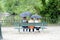 Park on a rainy day with three females sitting on a bench and holding umbrellas