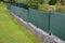 The park`s beautiful lawn is protected from the entrance from the street by a low fence made of gray galvanized steel. gate and ga