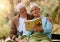 Park, senior and couple reading a book, relaxing and bonding outdoors with blanket. Love, retirement and elderly man and