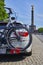 Parked car with a bike carrier attached to the stern and bicycles mounted on it. In the background you see the Berlin Siegessaeule