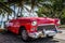 Parked red vintage car in Havana Cuba near the beach