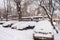 Parked snow-covered cars in the courtyard in winter cloudy morn