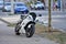 A parked sports bike is standing on the sidewalk in the city. The sports motorcycle is black and white