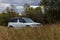 Parked white universal car for young travelers through the picturesque territories of nature reserves in the Pskov region, west of