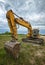 A parked yellow excavator on a meadow at sunset