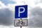 Parking bicycle sign on dull gray sky background.