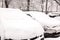 Parking cars after snowfall. Automobiles covered with snow. Winter concept
