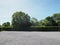 Parking lot sprinkled with gravel bush green tree blue sky nature background