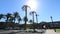 Parking lot with tall palm trees in front of arch in fortifying wall, sunny day