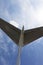 Part of aircraft tail and sunlit blue sky with clouds at background