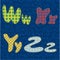 Part of the alphabet made of bright fabric-colored letters sewn onto denim.