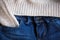 Part of blue jeans and woolen pullover close up. Selective focus