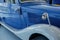 Part of blue perfect polished vintage car standing indoor at white tile